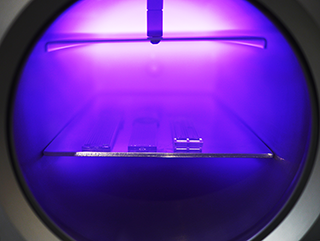 Oxygen plasma cleaning process inside a Henniker Plasma HPT-100 chamber showing purple plasma glow during surface treatment